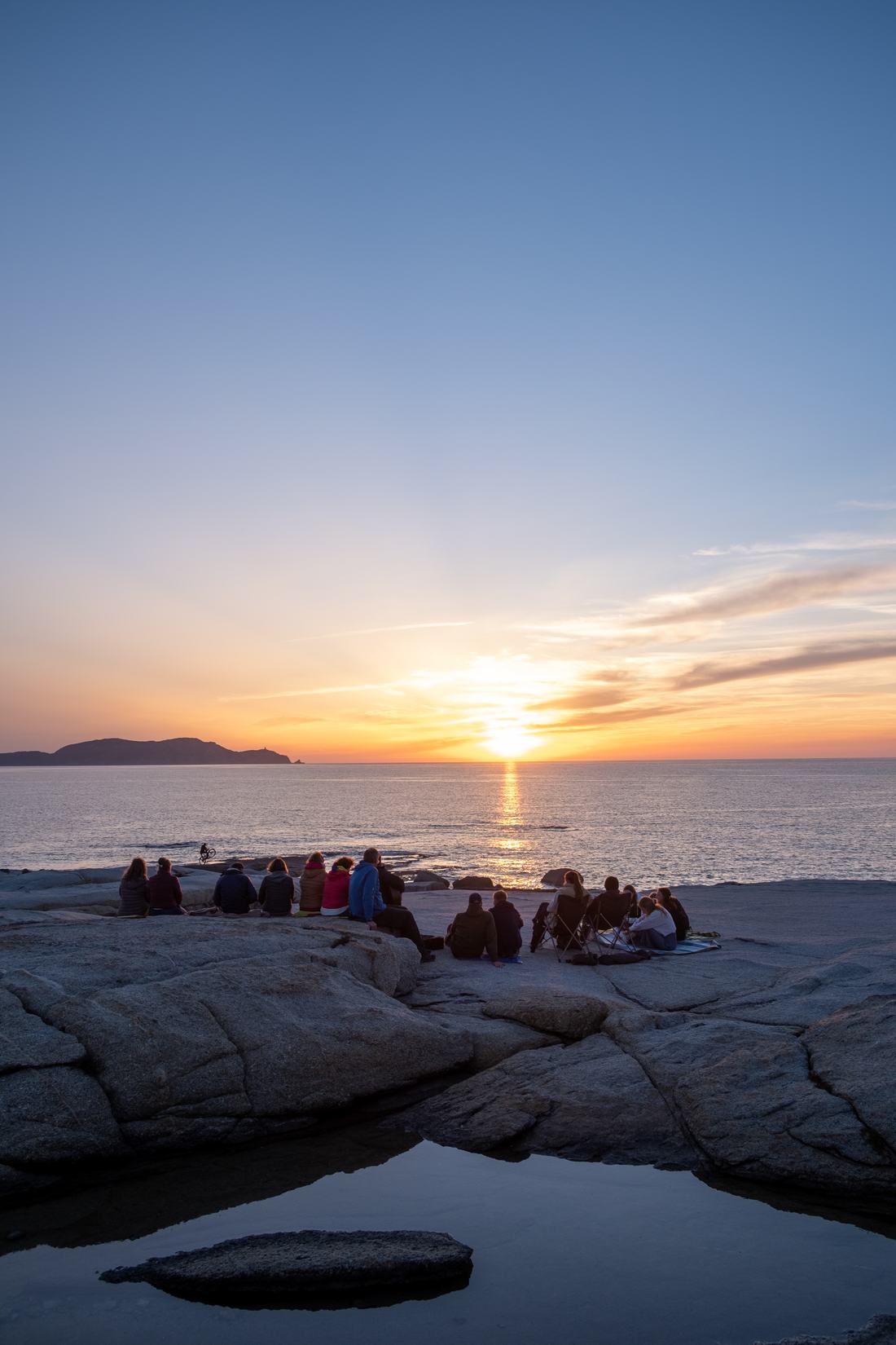 Gruppe bei Sonnenuntergang auf den Felsen am Meer